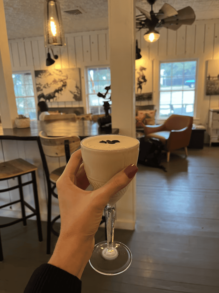 Chocolate latte in a glass cup at cozy coffee shop with wooden furniture and warm lighting.