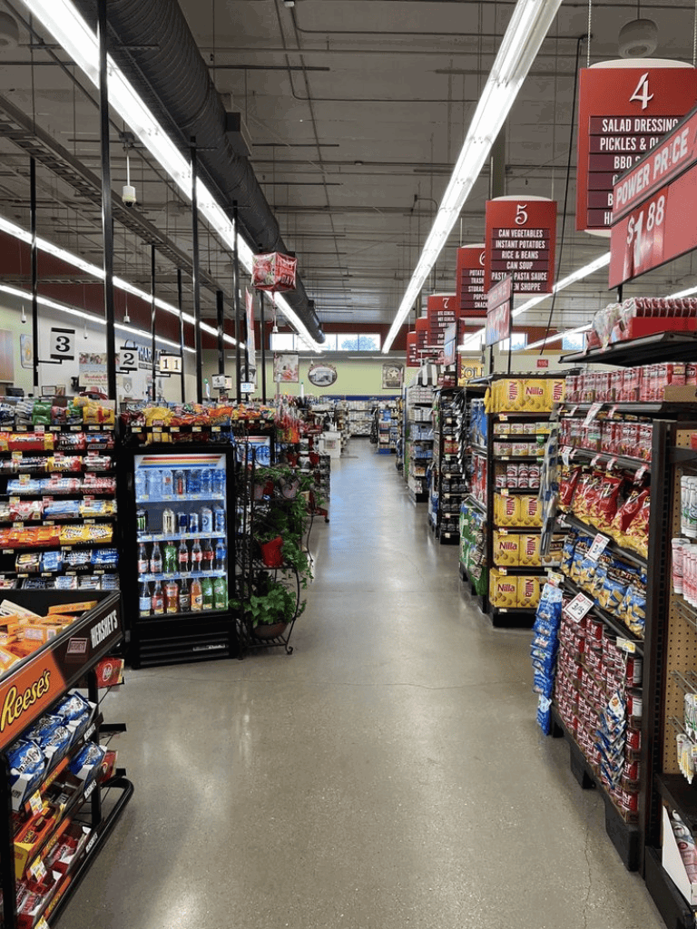 Bright grocery store aisle with packaged snacks and drinks, clear signage for food categories, organized shelves for easy shopping.