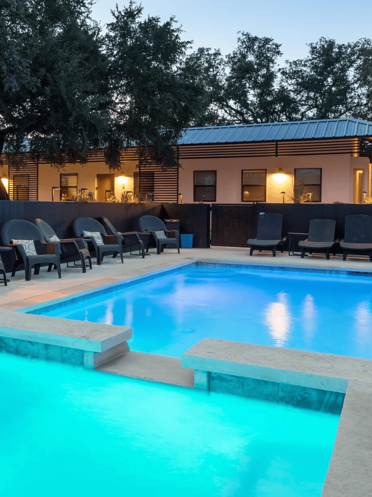 Relaxing outdoor hotel pool with ambient lighting and lounge chairs at dusk, perfect for guest comfort and leisure.