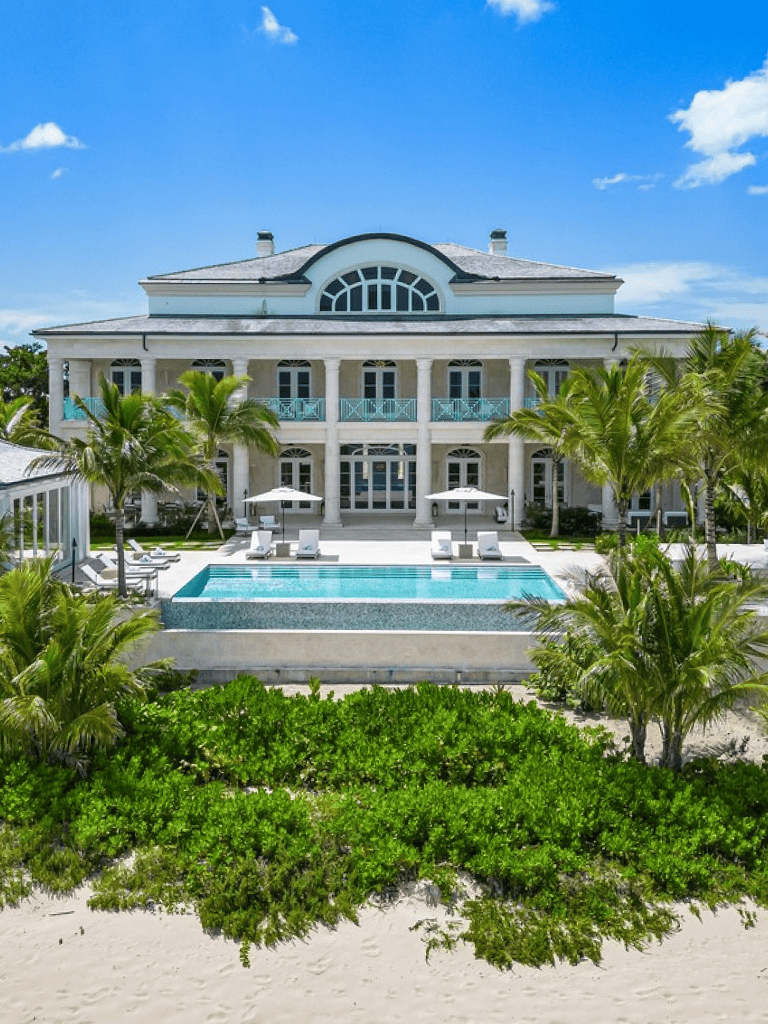Luxury beachfront villa with pool and tropical palm trees.