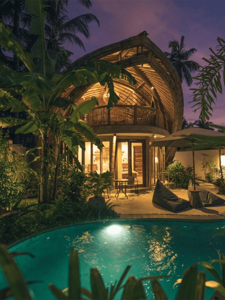 Luxurious tropical villa with pool and jungle surroundings at dusk.