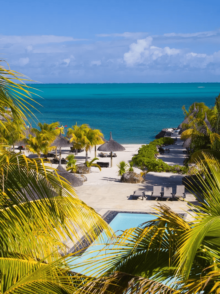 Tropical beach resort with ocean view, palm trees, and pool, paradise vacation destination.