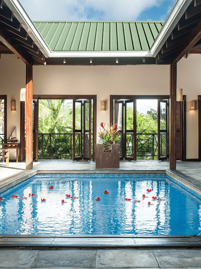 Luxurious indoor swimming pool with skylight and tropical greenery, perfect for relaxation and wellness.