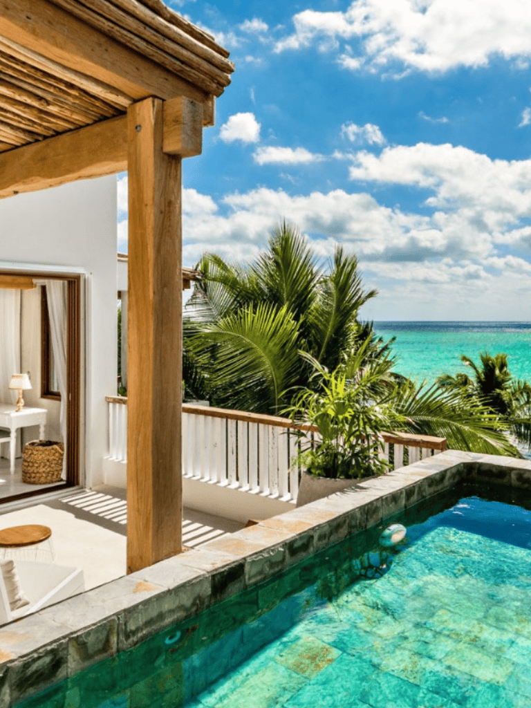 Sunlit tropical villa with ocean view, private pool, and lush greenery, perfect for vacation relaxation.