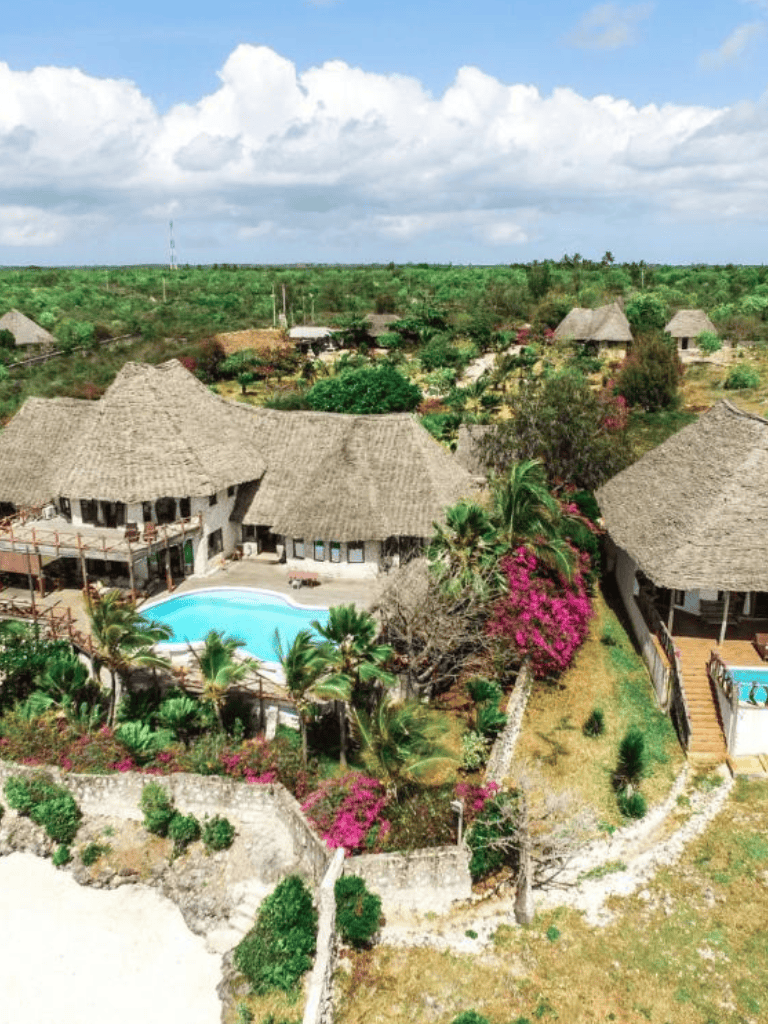 Luxury eco-resort with thatched roofs, swimming pool, tropical gardens in a serene village setting.