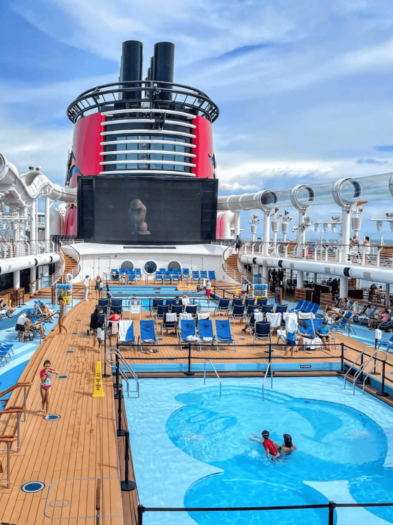 Bright cruise ship pool deck with water slides and lounging area, tropical vacation destination.