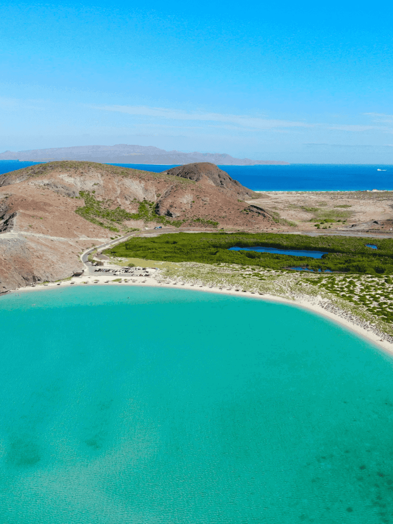 Vast coastal landscape with turquoise lagoon, mountains, and blue sea, enhancing travel and adventure planning.
