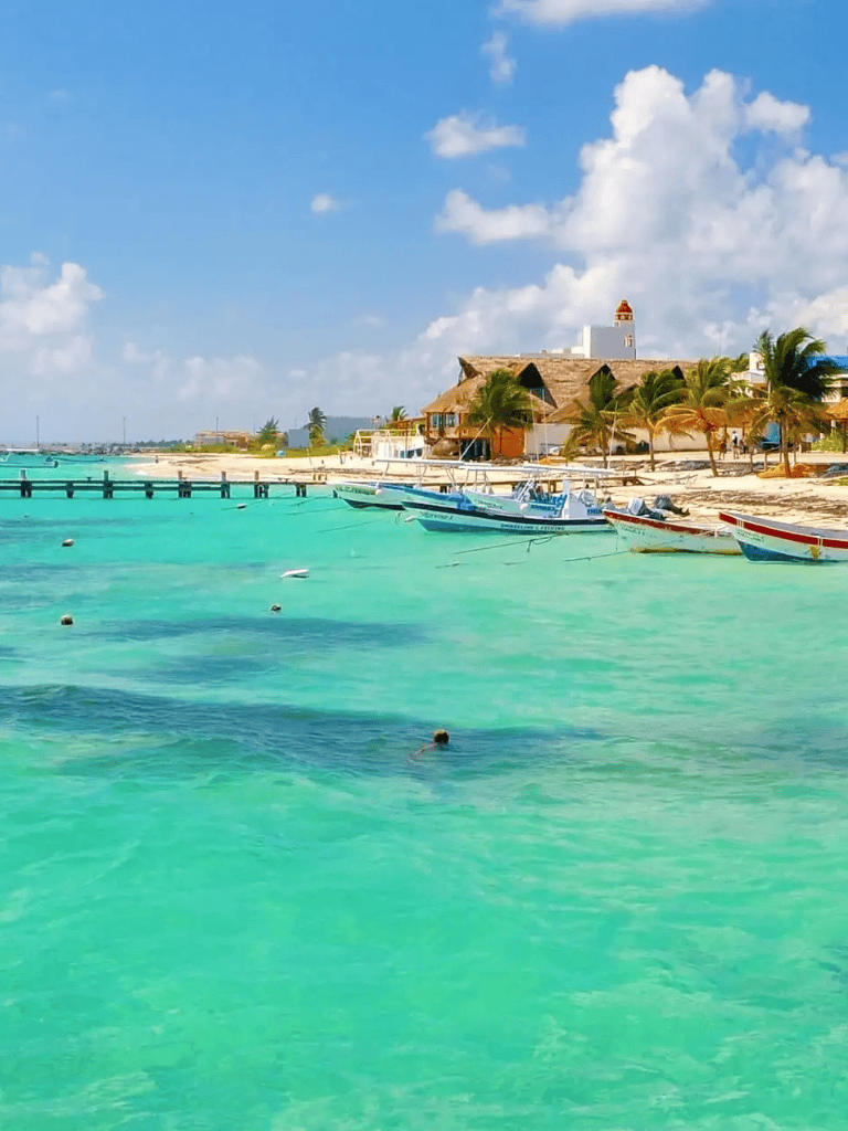 Relaxing Caribbean beach with turquoise water and boats, perfect for vacation and travel planning.