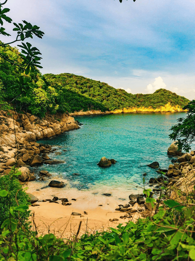 Secluded tropical beach with clear turquoise waters and lush green hills.
