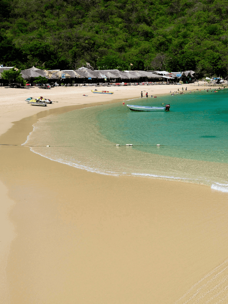 Pristine beach with turquoise waters, boats, and tropical huts at QuestForDirections.