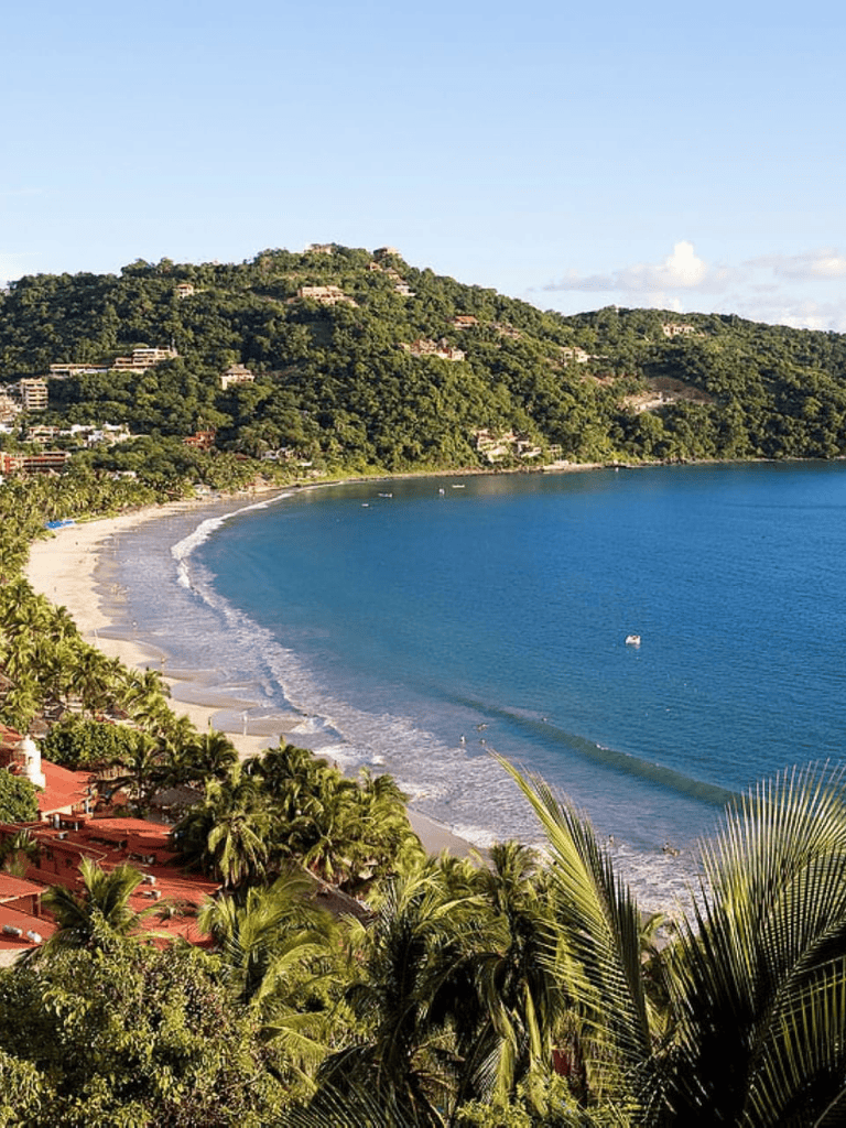 Luxurious coastal hillside resort overlooking a tropical beach and clear ocean waters.