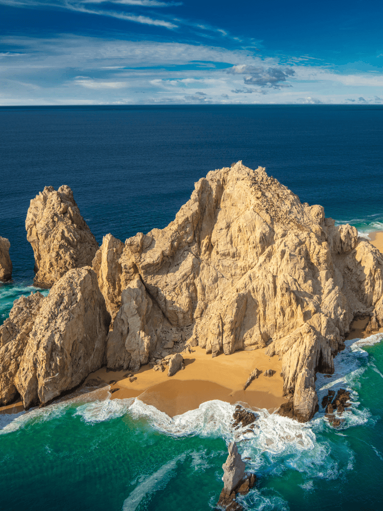 Cliffside beach with large rocks and ocean waves, scenic coastal landscape.