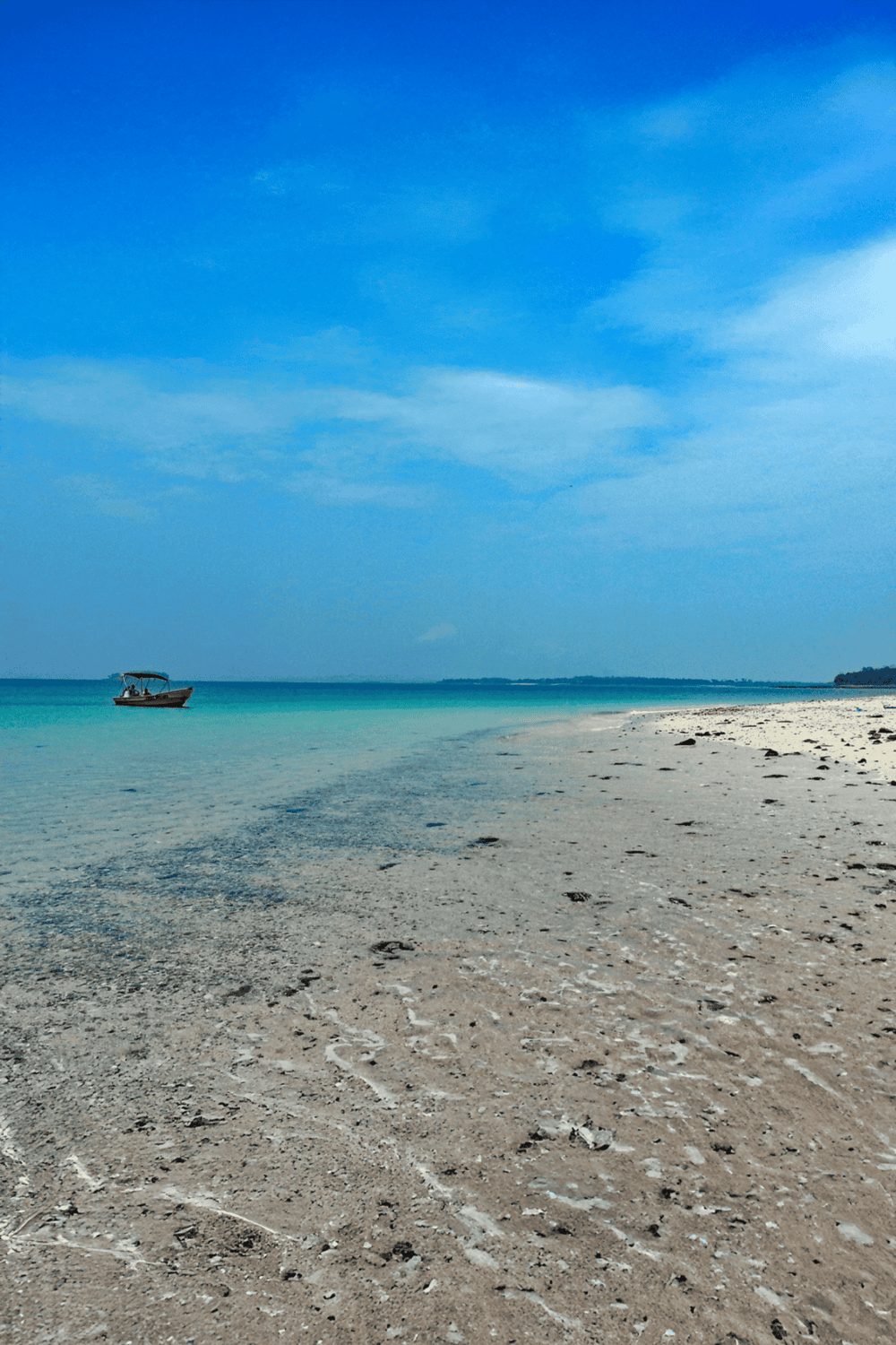 Secluded beach with clear turquoise waters and boat, perfect for relaxation and ocean adventures.