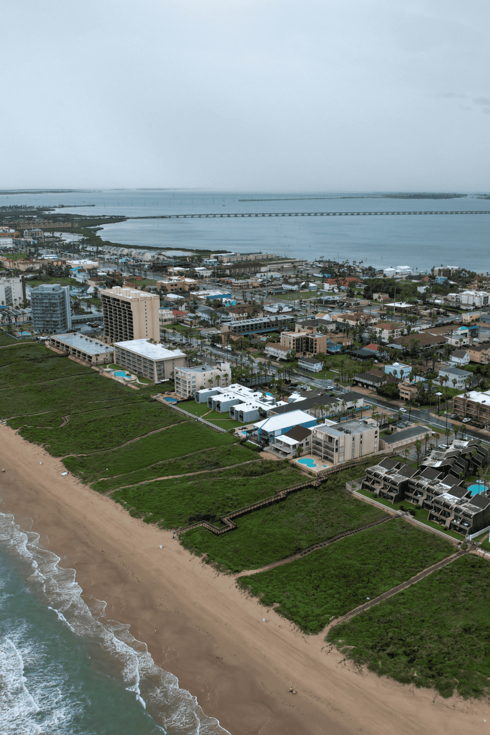 Aerial view of coastal city with beachfront hotels and ocean, showcasing QuestForDirections' travel guidance services.
