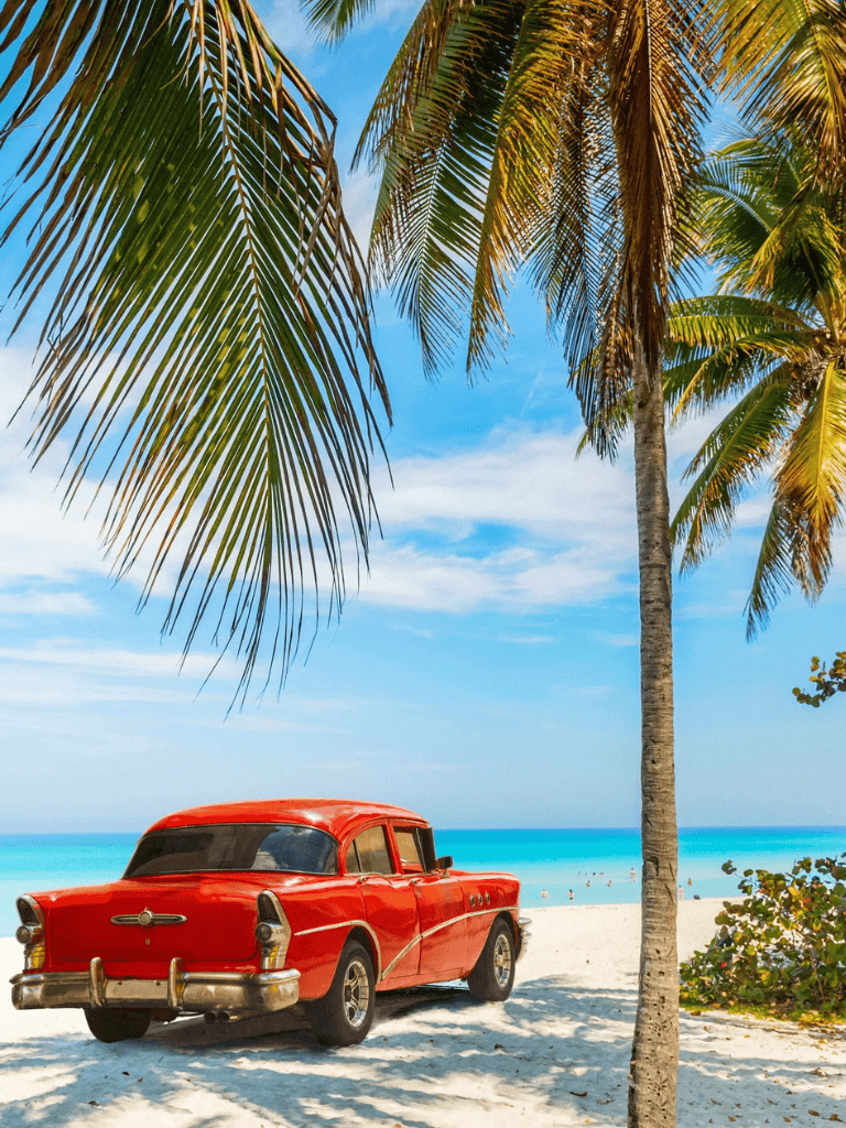 Vintage red car on tropical beach under palm trees, sunny sky, relaxing getaway destination, travel, vacation.