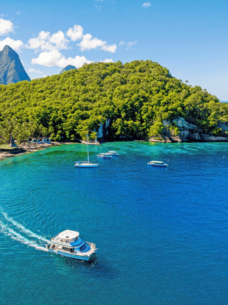 Boats cruising near lush island with scenic views and clear blue waters.