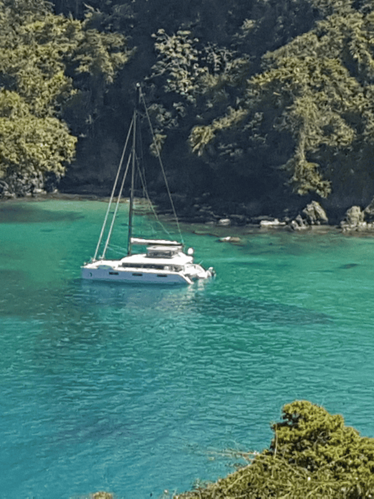 Serene yacht sailing in clear turquoise waters surrounded by lush green islands.