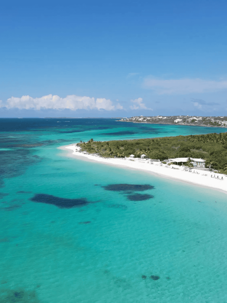 Pristine turquoise beach with lush green coastline and clear blue sky, ideal for travel and adventure.