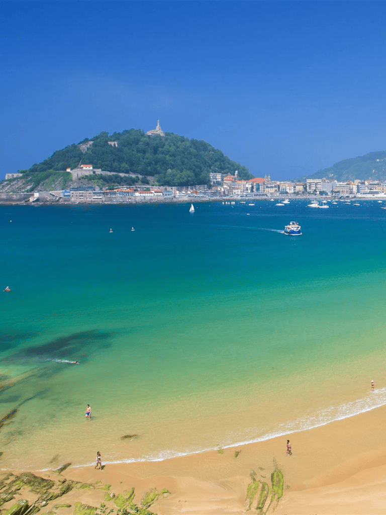 Scenic beach with turquoise waters and coastal city view in San Sebastián, Spain.