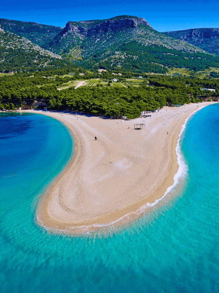 Pristine beach with turquoise waters and lush greenery in a scenic coastal landscape.
