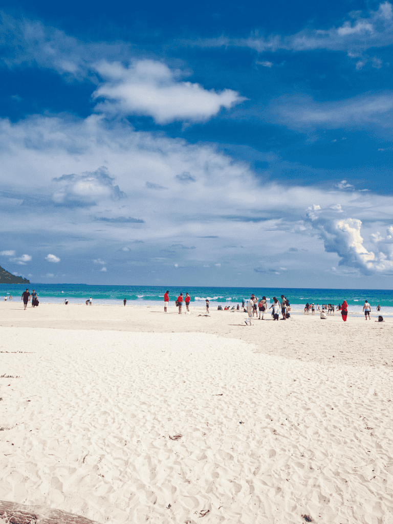 Bright sunny day at the beach with families enjoying the ocean view and white sand shoreline. Perfect for seaside relaxation and outdoor fun.