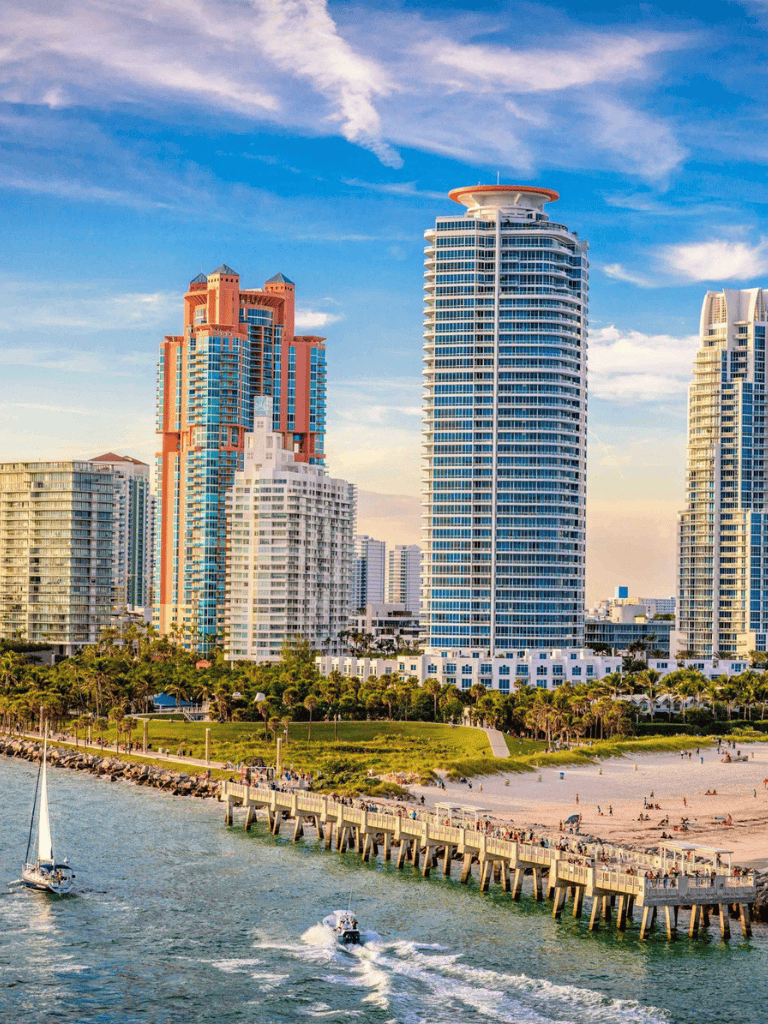 Modern Miami Beach skyline with high-rise buildings overlooking the ocean, featuring boats and scenic waterfront views.