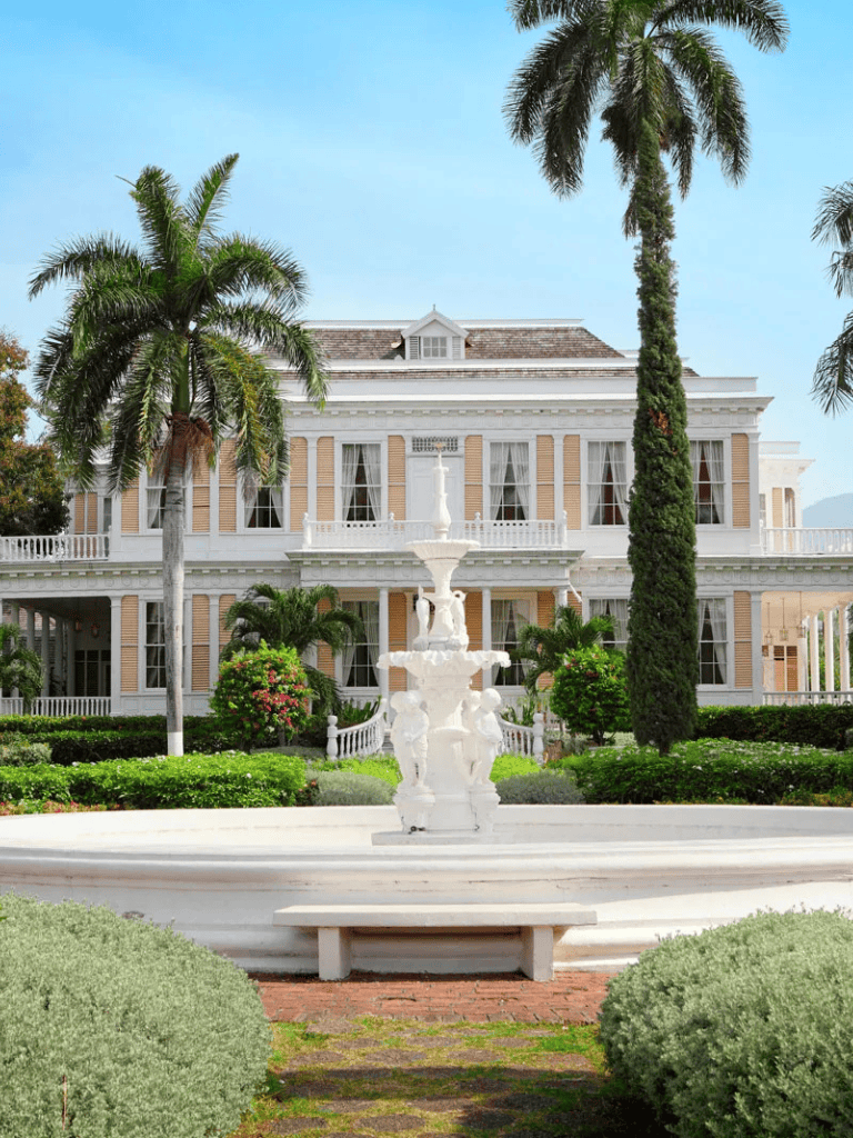 Elegant historic mansion with lush tropical landscaping and a decorative fountain, perfect for events and private gatherings.