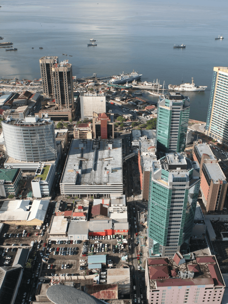 Modern city skyline with tall skyscrapers and a busy port along the waterfront, showcasing urban development and maritime activity.