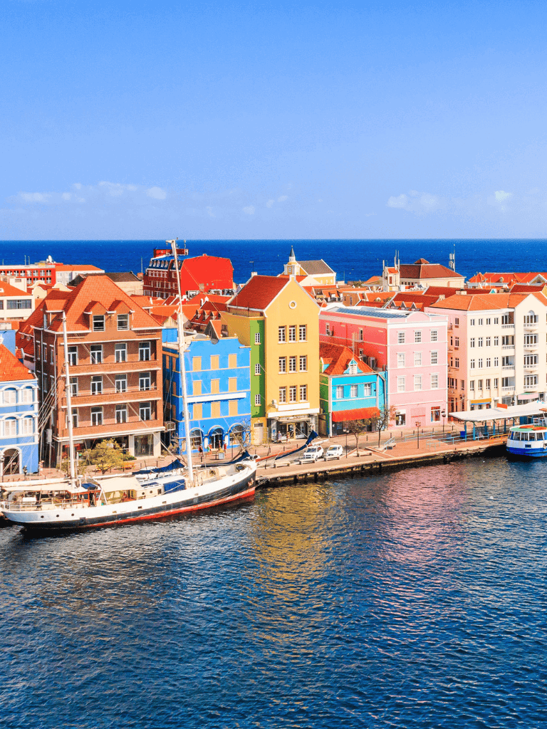 Colorful harbor town skyline with boats and ocean view, popular for travel and tourism.