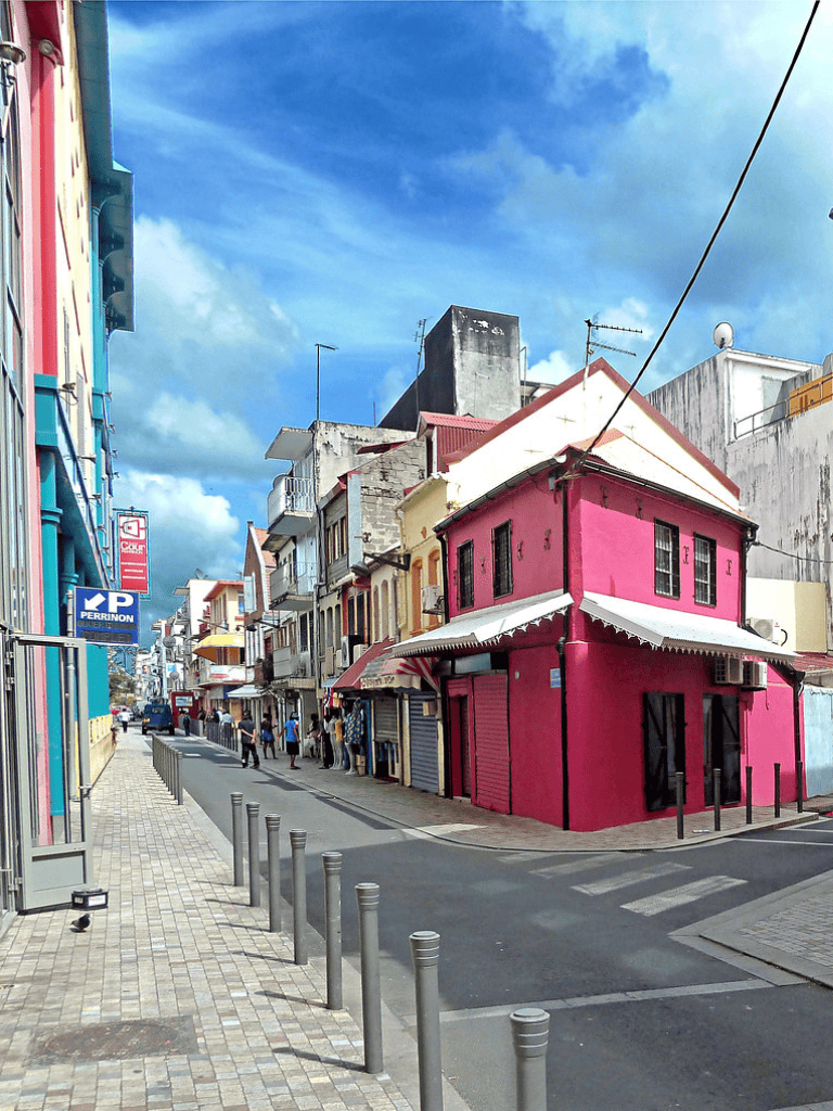 Colorful street scene in Mexico with vibrant pink building, shops, and pedestrians.