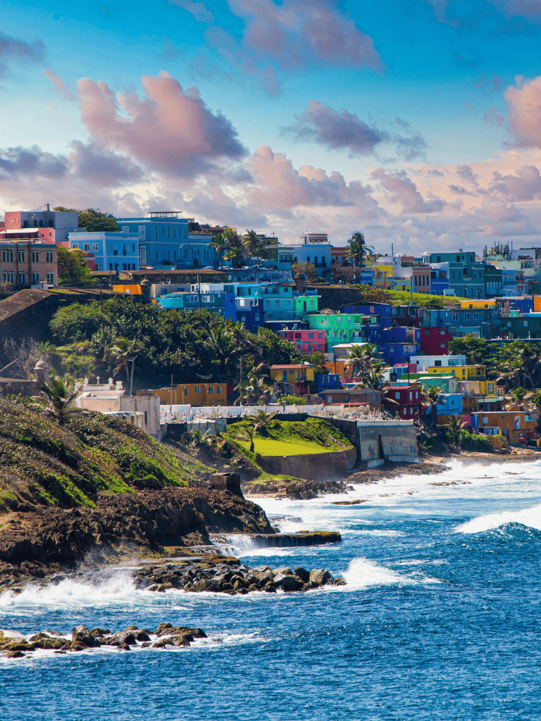Colorful coastal town with vibrant houses on seaside cliffs, ocean waves, and scenic skyline.