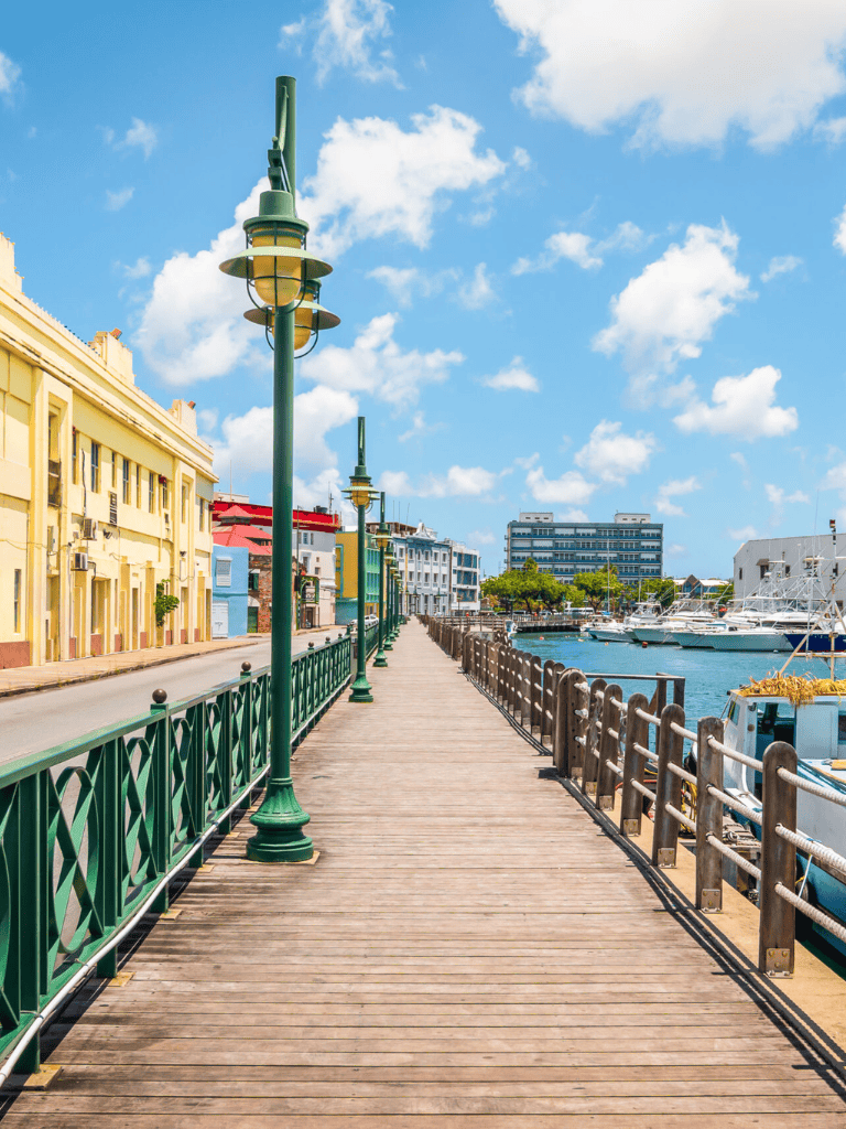 Colorful waterfront promenade with lamps, boats, and modern buildings on sunny day.