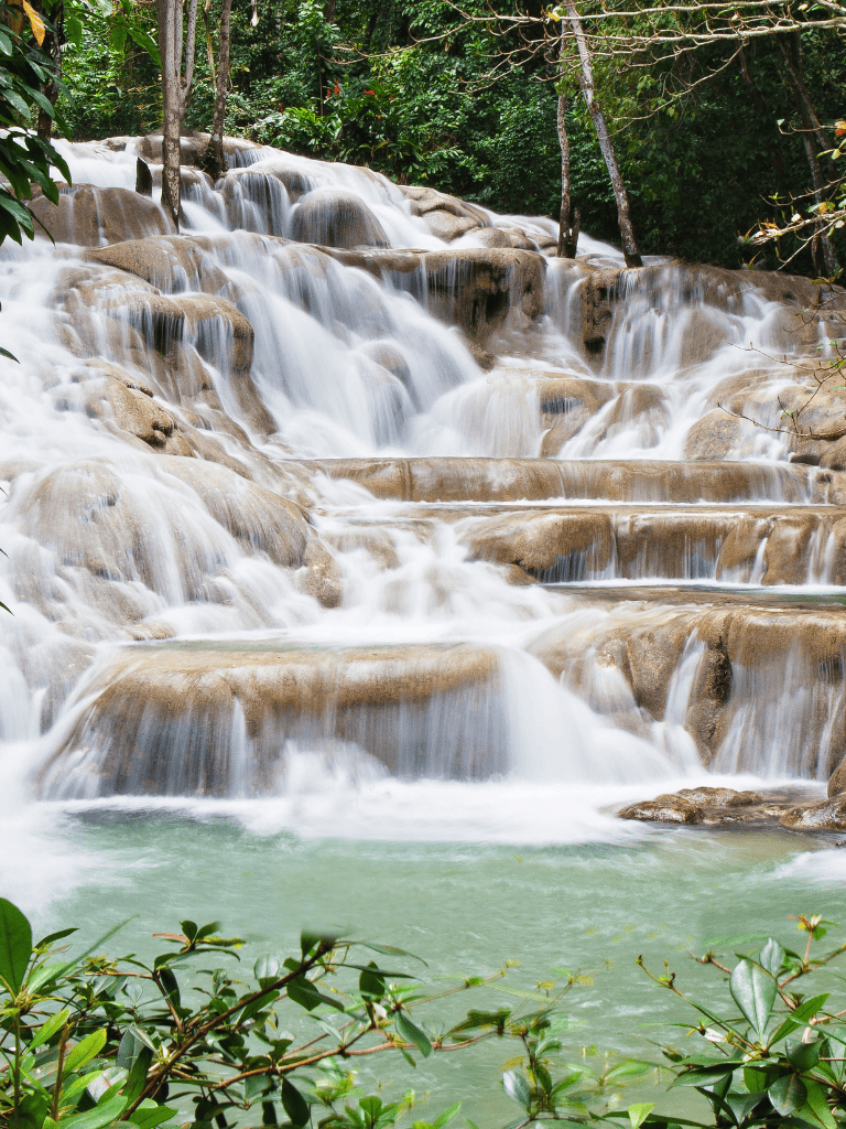Serene waterfall surrounded by lush green jungle, tropical nature landscape, tranquil waters, and cascading rocks.