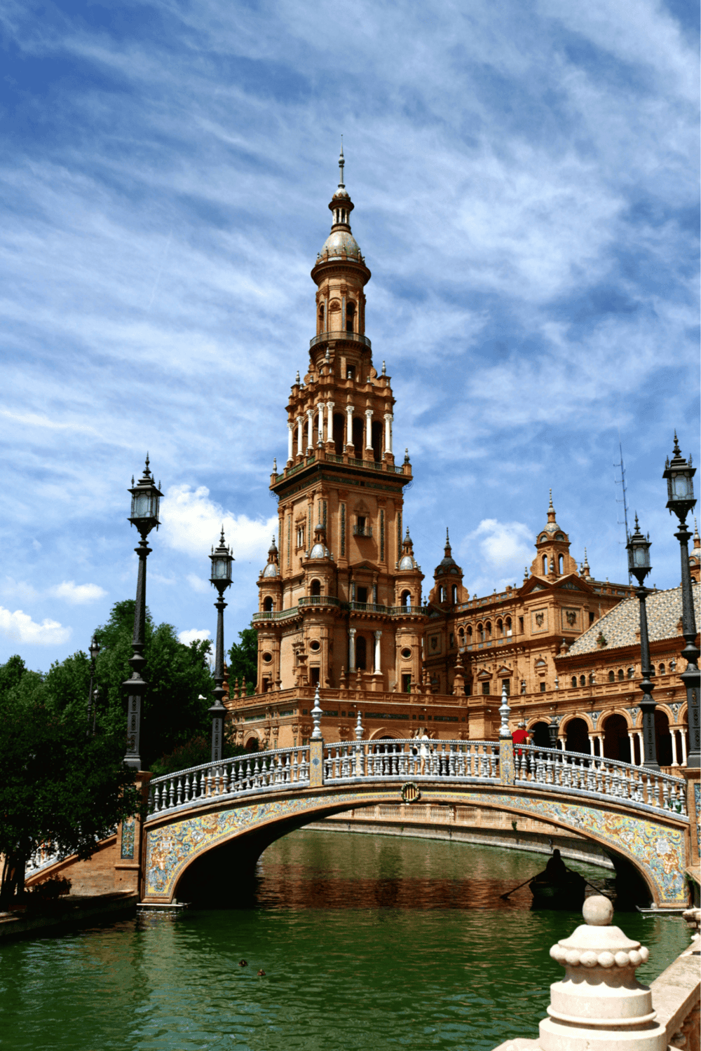 Golden Renaissance-style castle with intricate architecture and a scenic bridge over water, set against a blue sky.