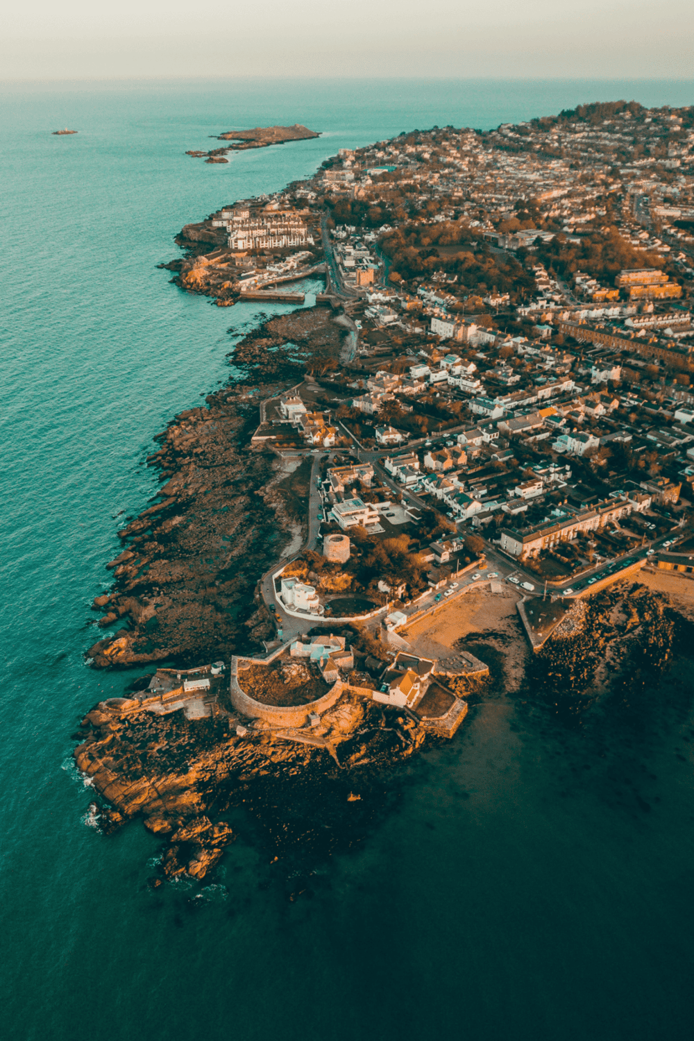 Coastal town aerial view with historic sites, scenic ocean views, and vibrant cityscape.