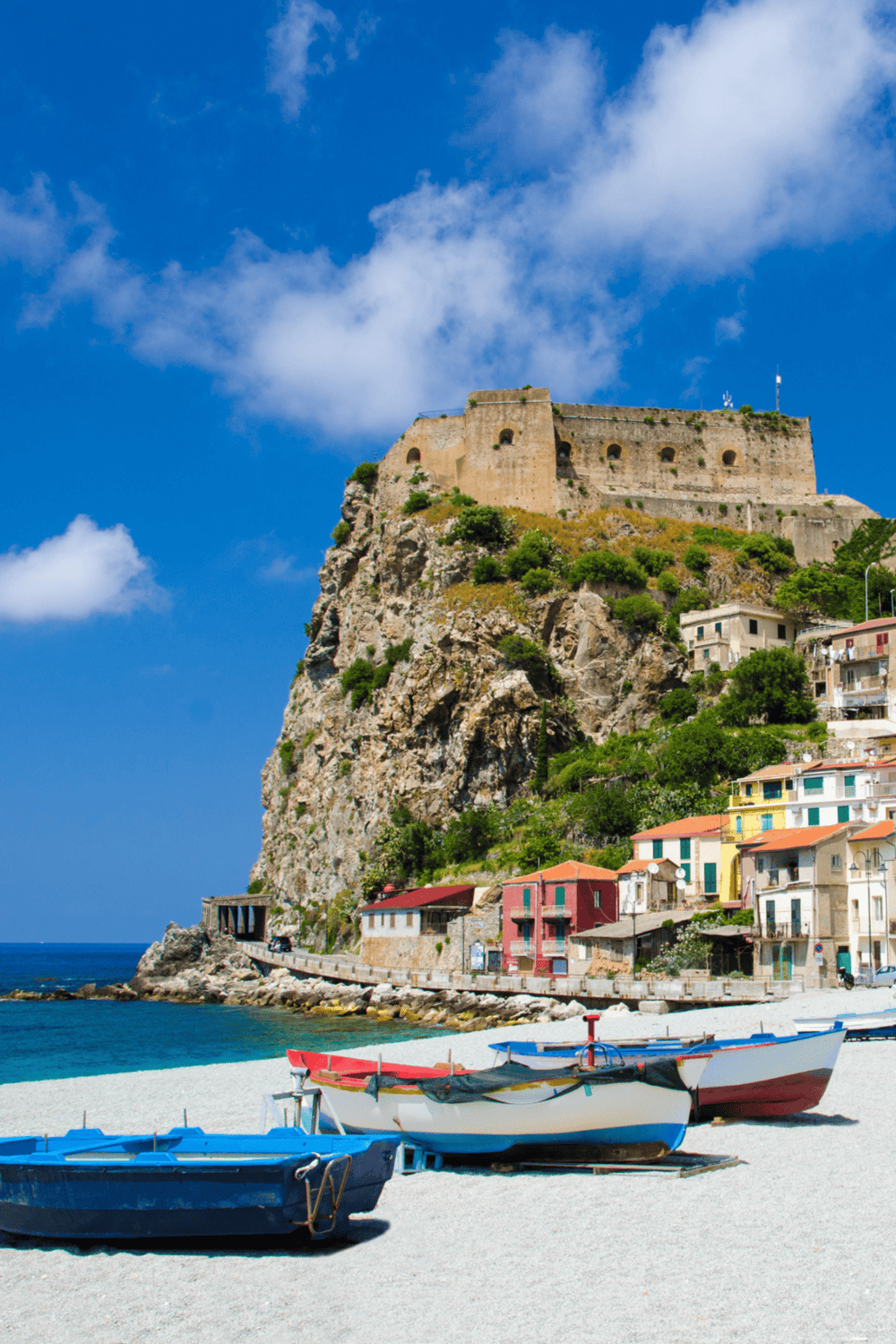 Cliffside Castel in Positano, Italy with colorful seaside buildings and boats at the beach.