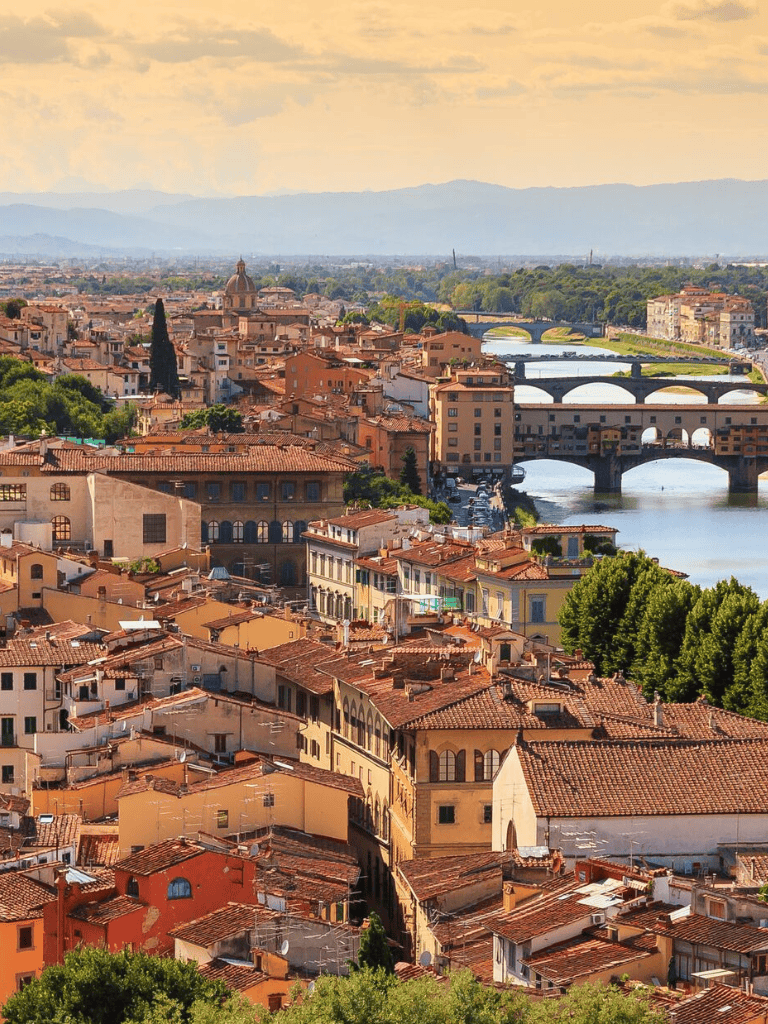 Panoramic view of Florence, Italy, showcasing historic architecture, bridges, and the Arno River.