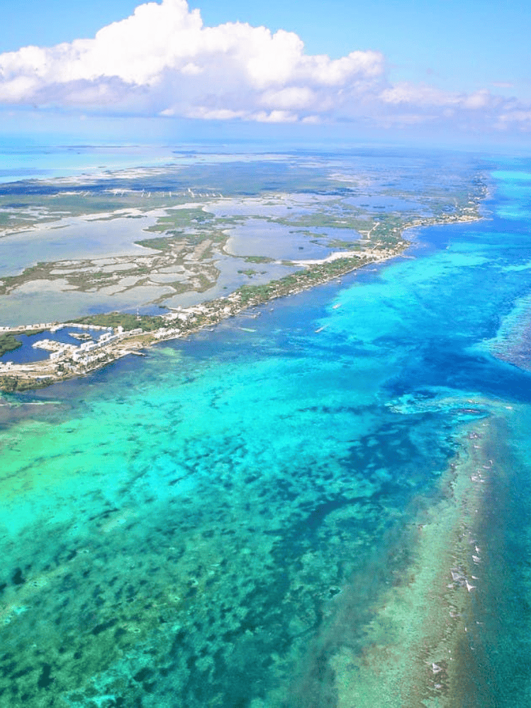 Aerial view of a coastal region with turquoise waters, wetlands, and nearby residential areas, showcasing scenic island landscapes.