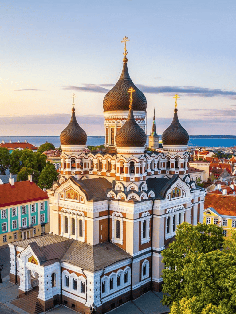 Orthodox church with onion domes and historic architecture in Tallinn, Estonia at sunset.