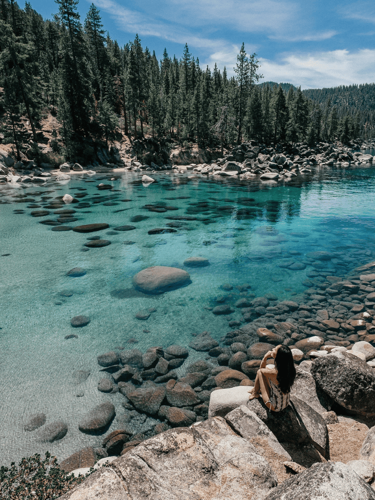 Tranquil mountain lake with clear turquoise water and lush forest background.