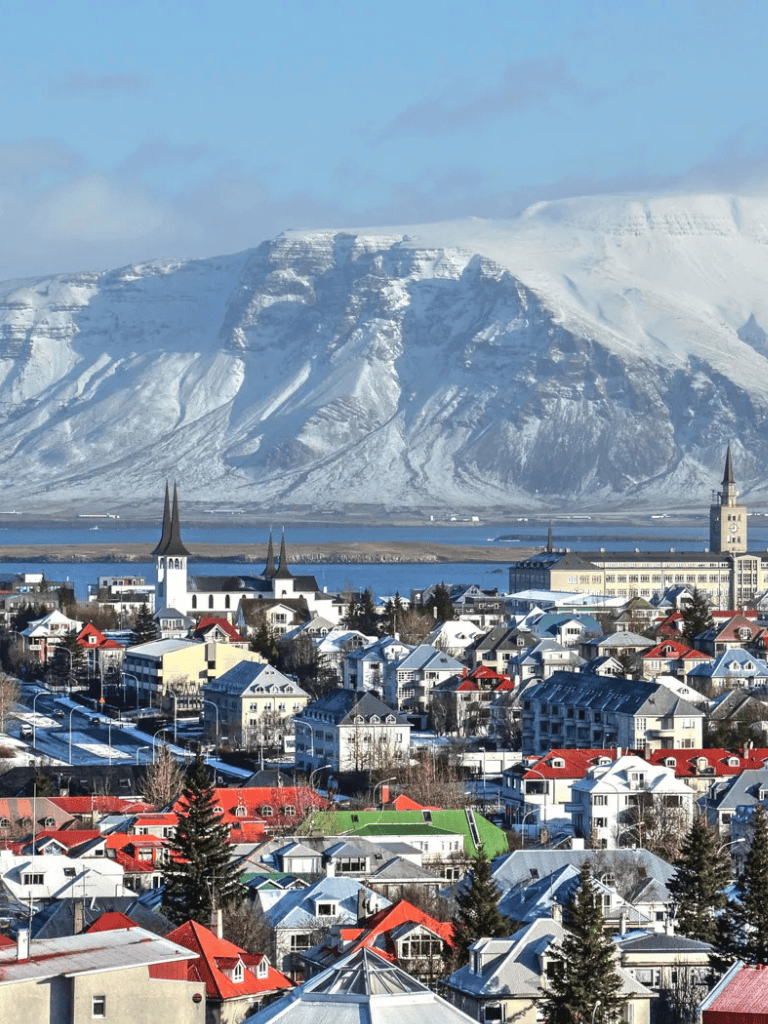 Vibrant cityscape with colorful rooftops and snowy mountains in the background, showcasing Iceland's scenic beauty.