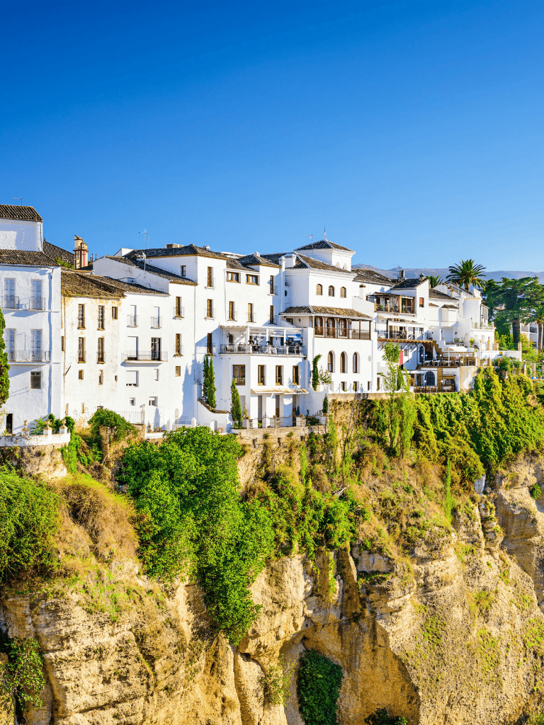 White cliffside houses in Andalusia, Spain under a clear blue sky.