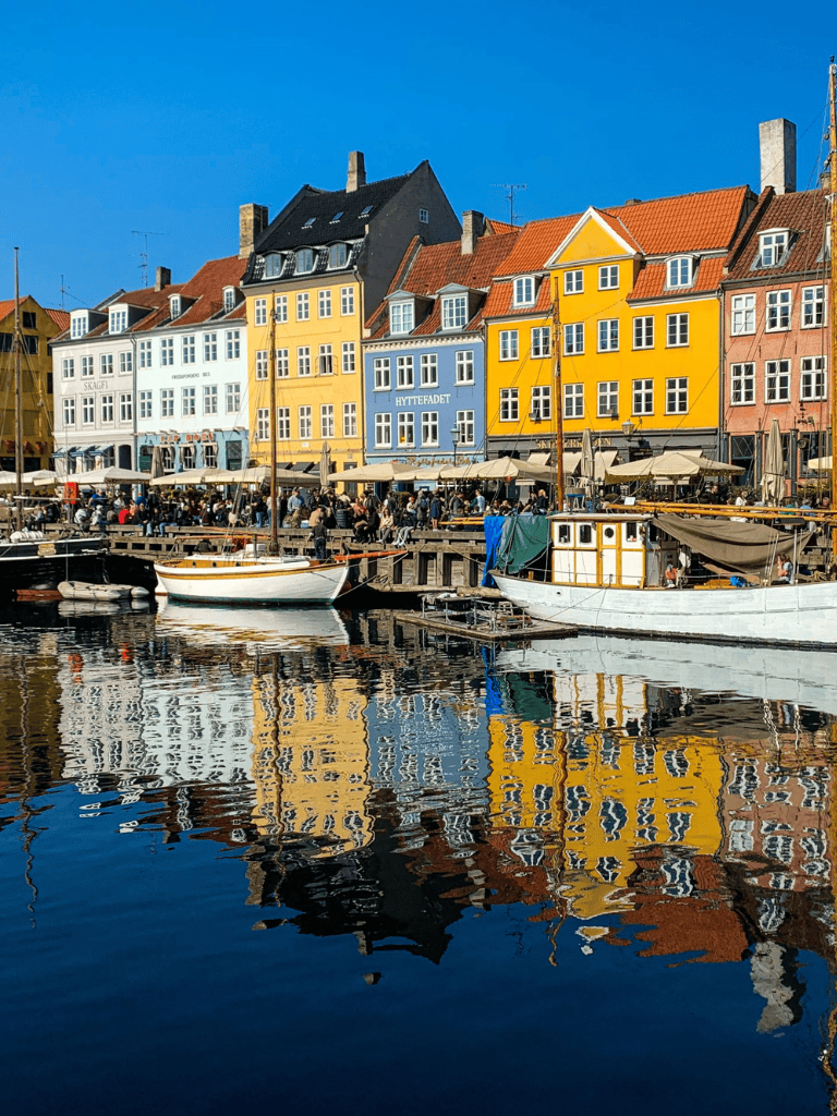 Colorful Nyhavn waterfront with boats and historic buildings in Copenhagen, Denmark, popular for sightseeing and dining.