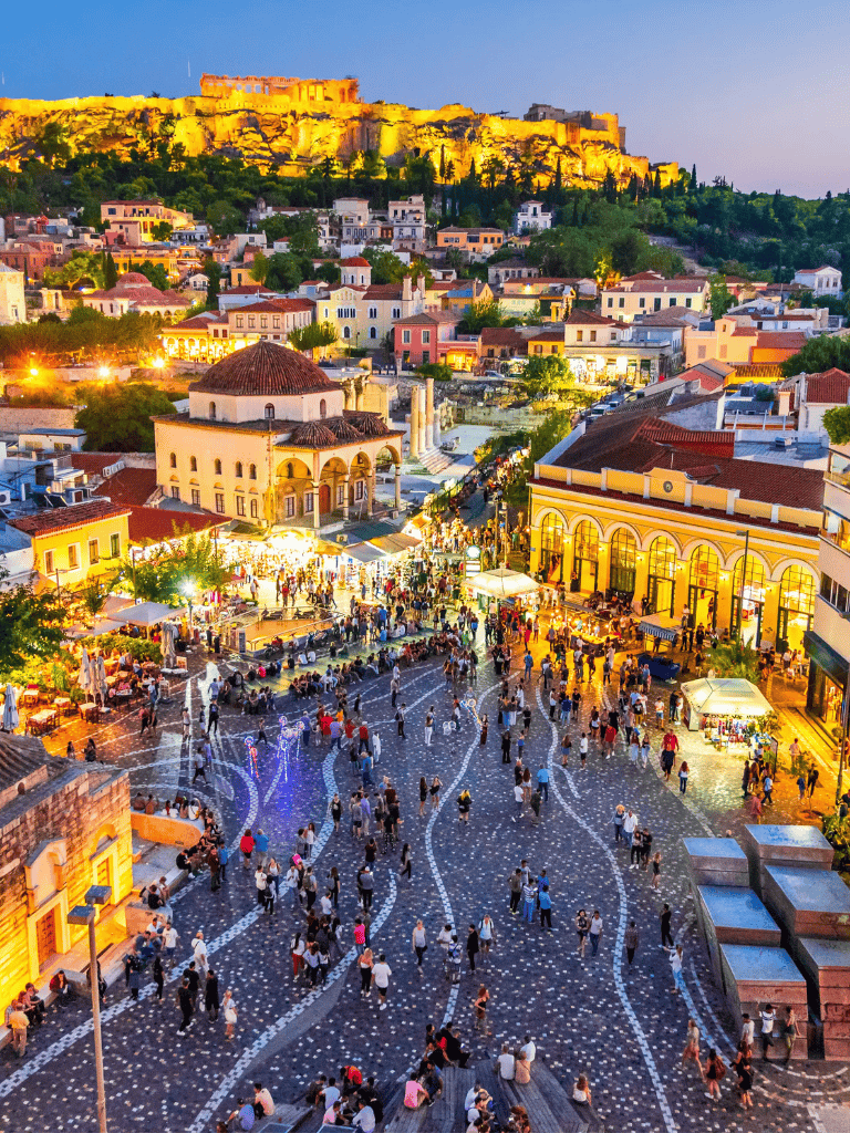 Vibrant evening scene of Monastiraki Square with historic architecture and a lively crowd in Athens, Greece.