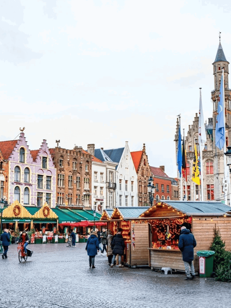 Colorful European town square with Christmas market stalls and historic architecture.