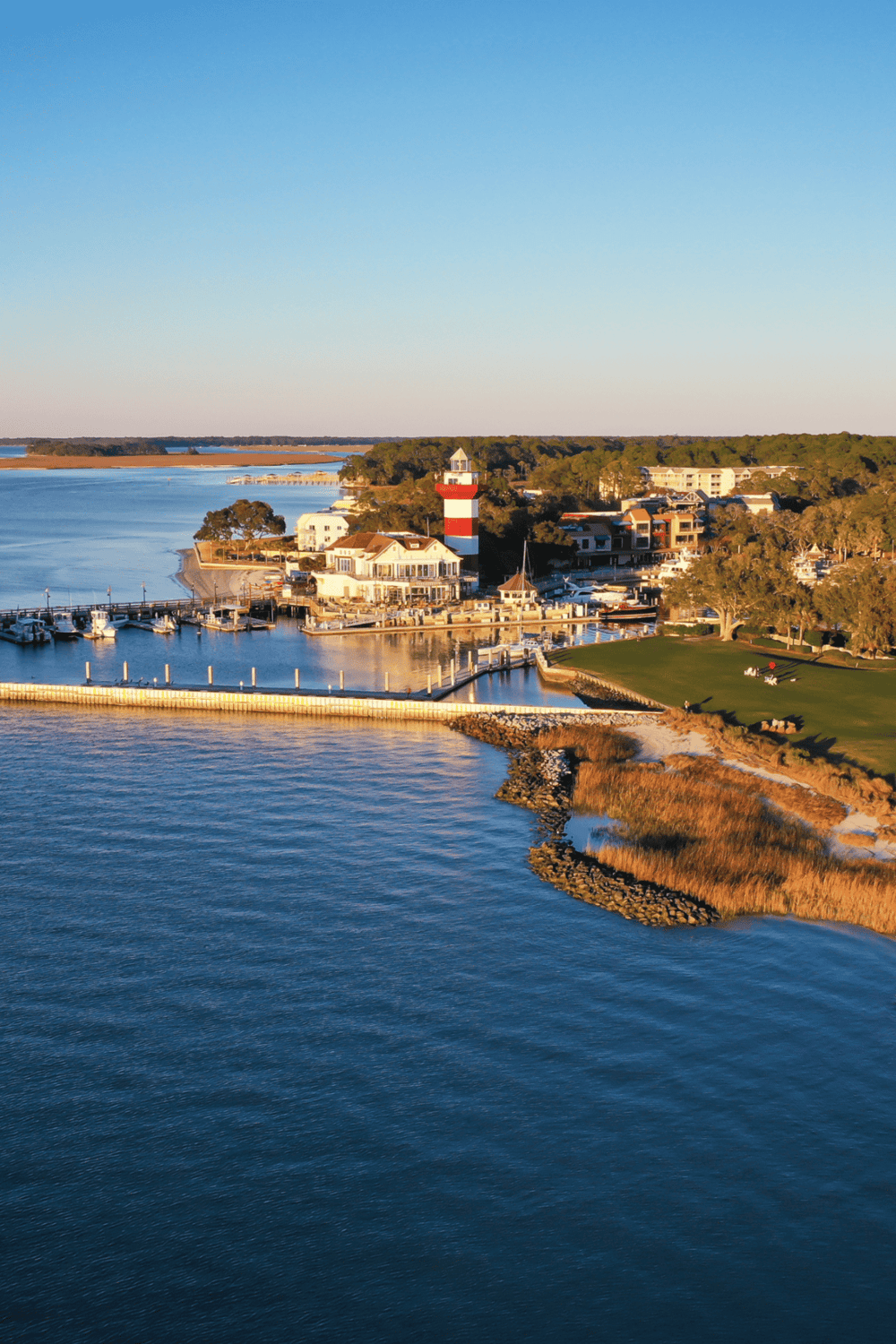 Lighthouse and marina at a scenic waterfront, showcasing QuestForDirections' navigation and travel solutions.