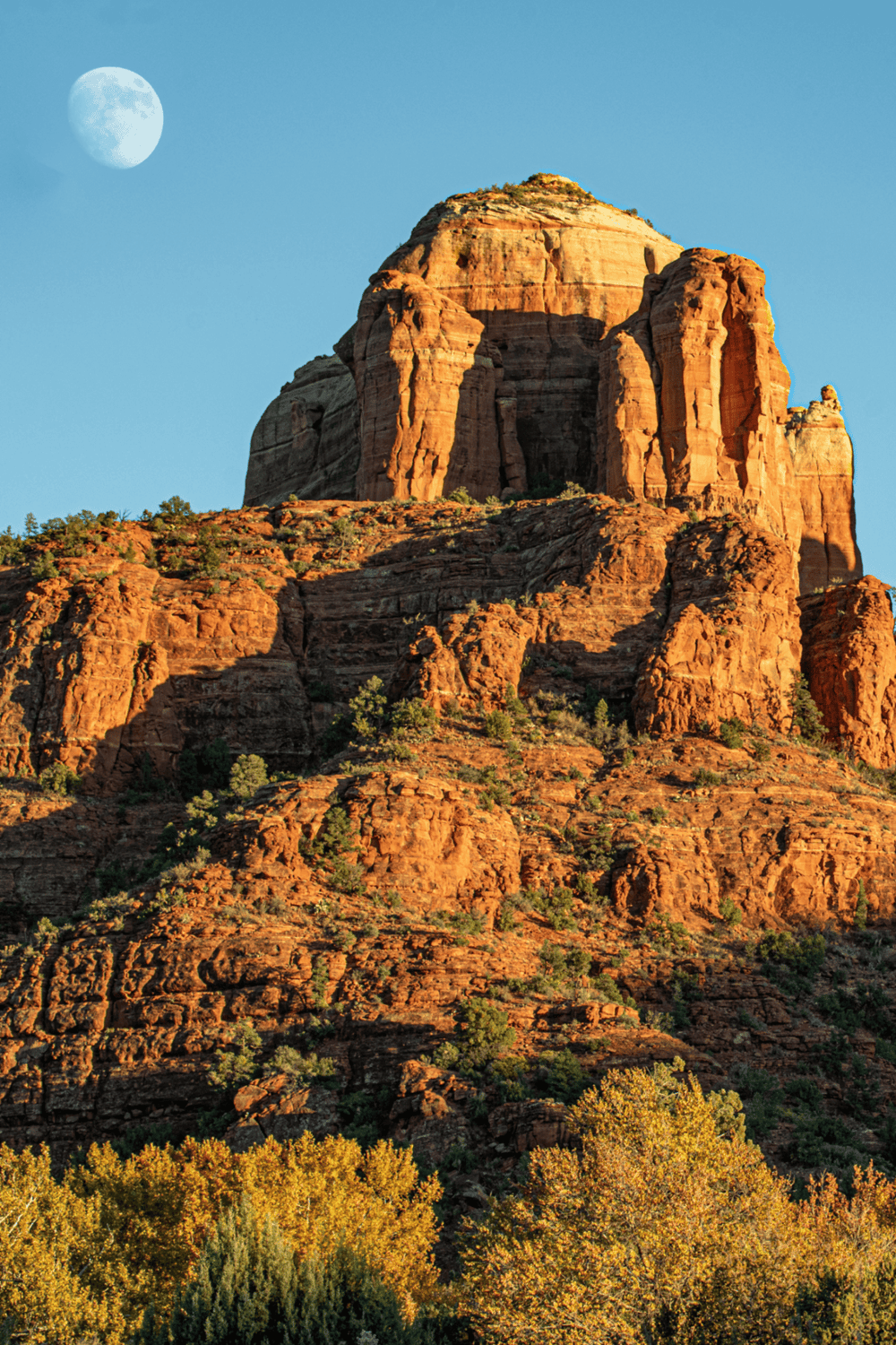 Majestic rock formation in Sedona, Arizona under clear blue sky at sunset.