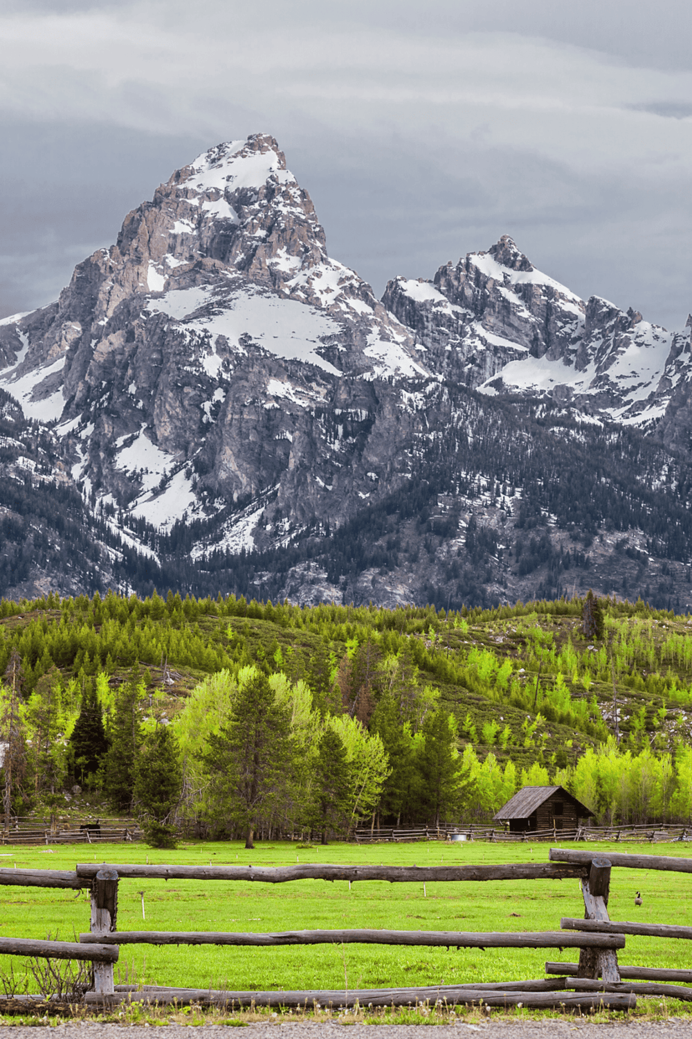 Snow-capped mountain landscape with lush greenery and rural cabin, perfect for outdoor adventure and travel inspiration.