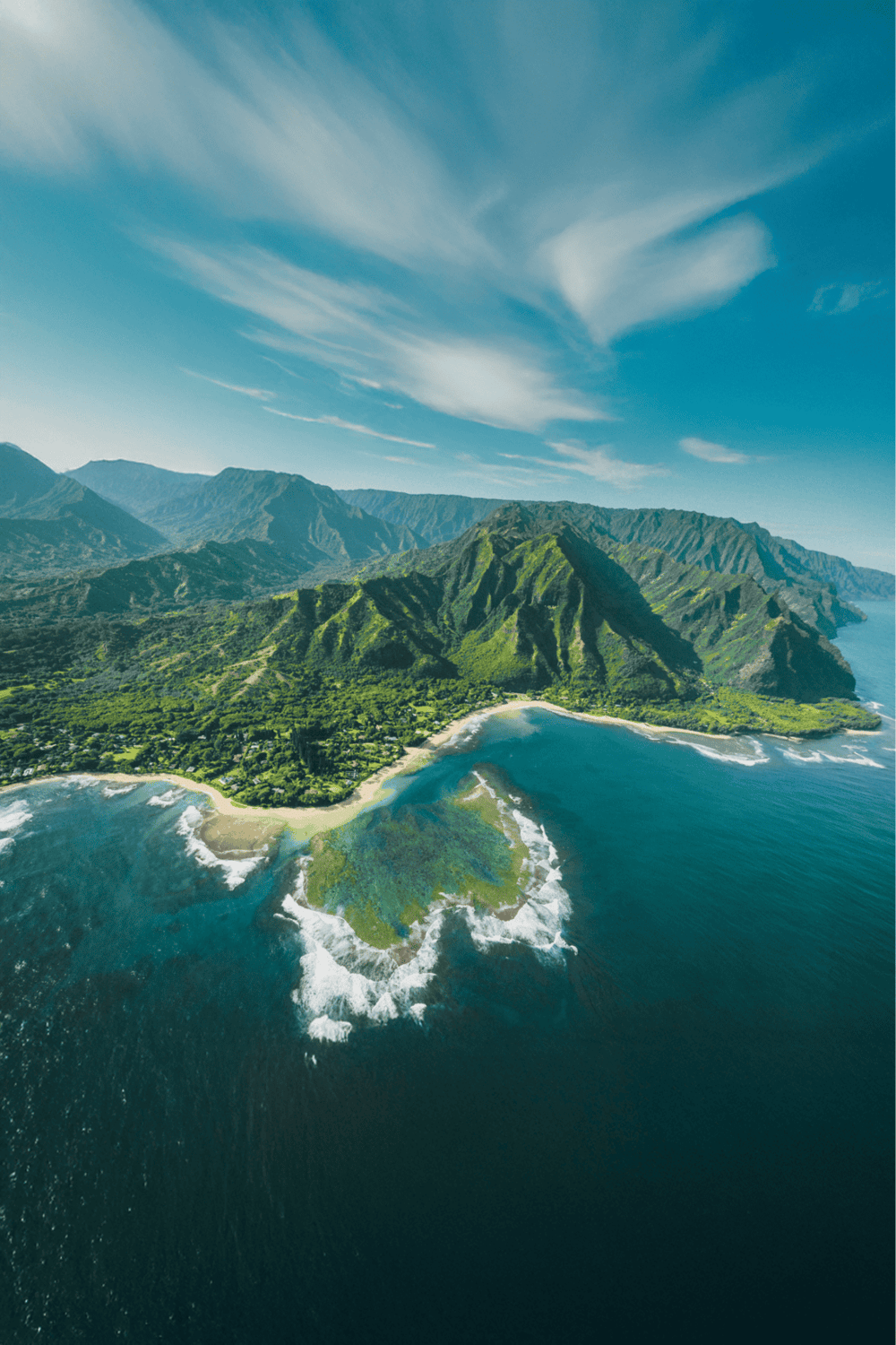 Vibrant aerial view of lush green Hawaii coastline with mountains and ocean waves.