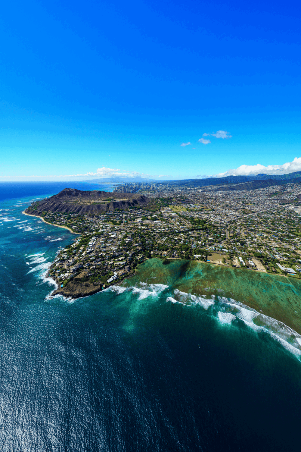 Aerial view of Honolulu, Hawaii, showcasing mountains, ocean, and coastal neighborhood landmarks.